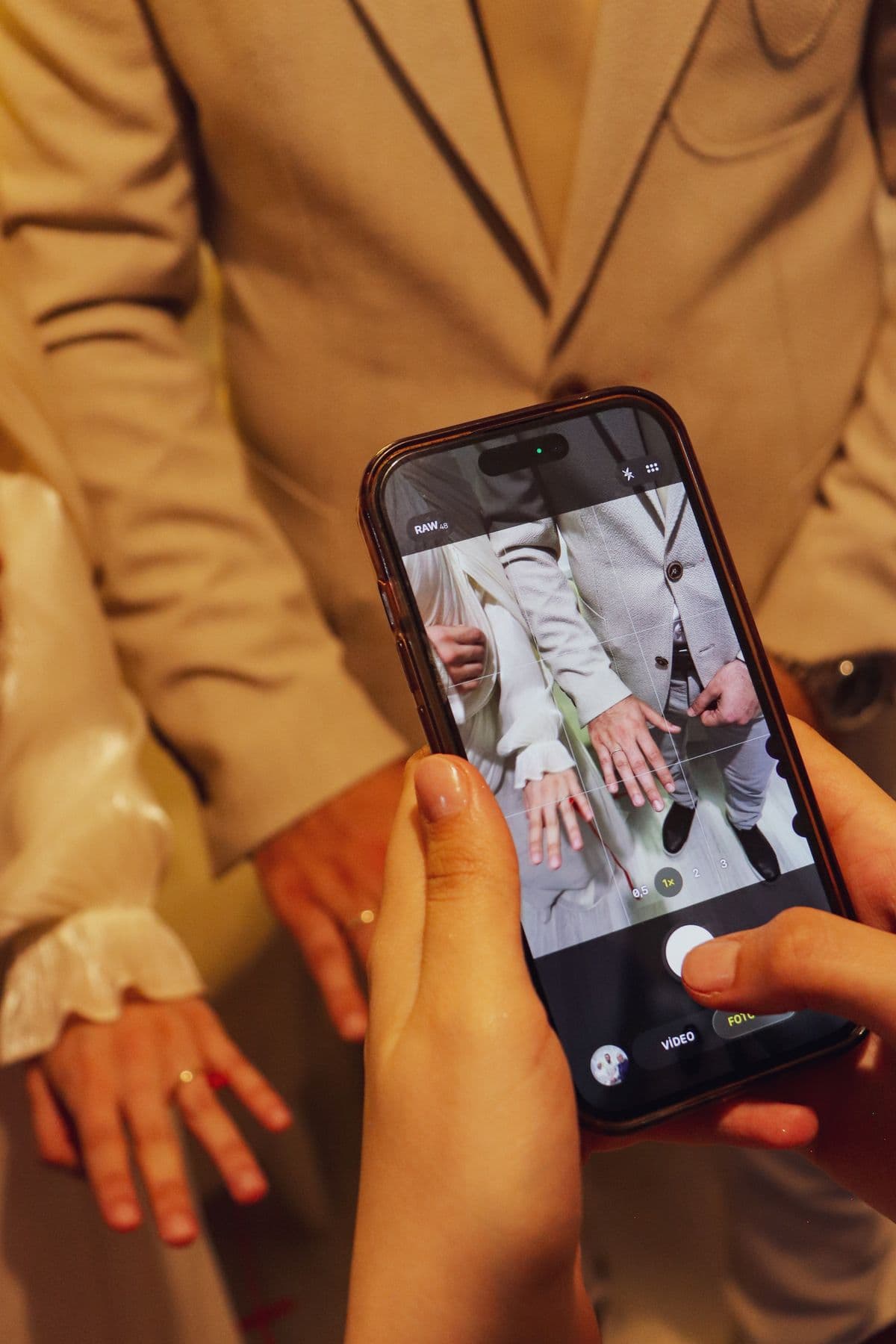 Hands holding a smartphone capturing a wedding moment — how guests experience an interactive wedding invitation