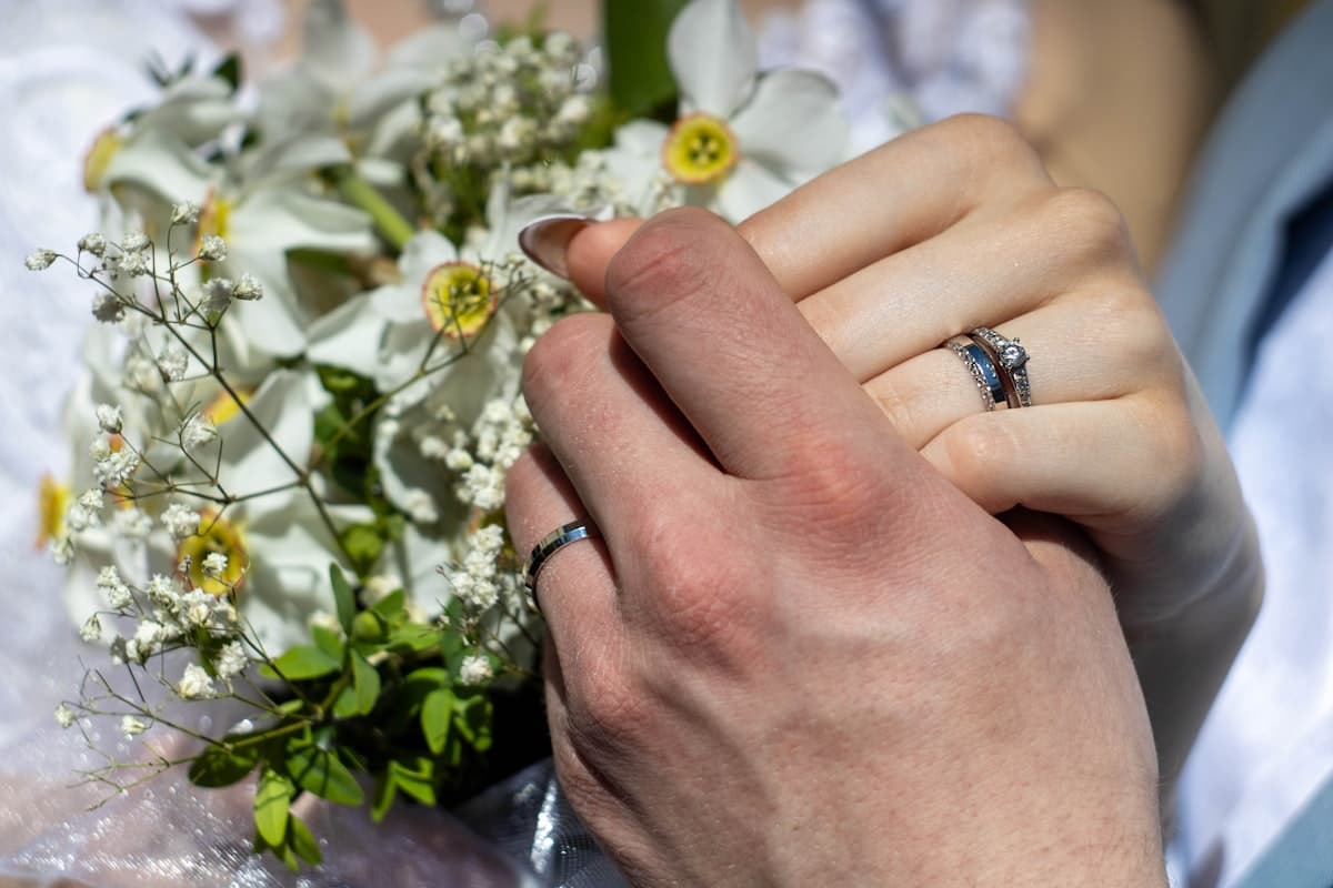 Wedding couple holding hands with rings and bouquet — the emotional detail a cinematic wedding invite captures in scroll sections