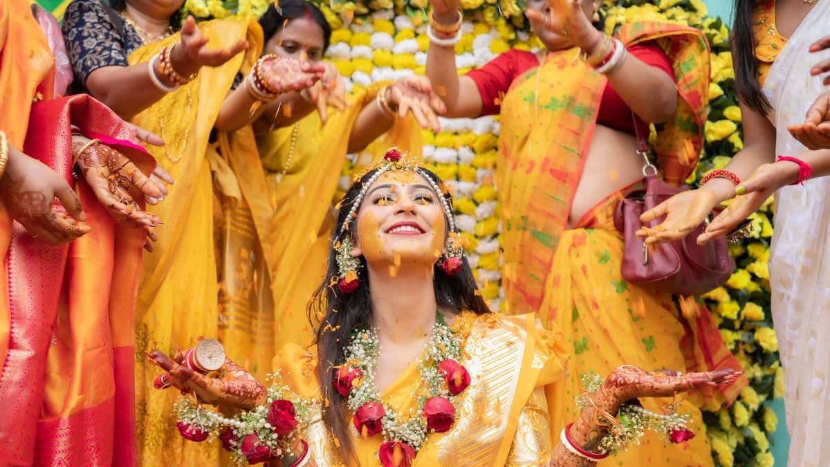 Women applying turmeric paste to bride during Indian pre-wedding haldi ceremony celebration