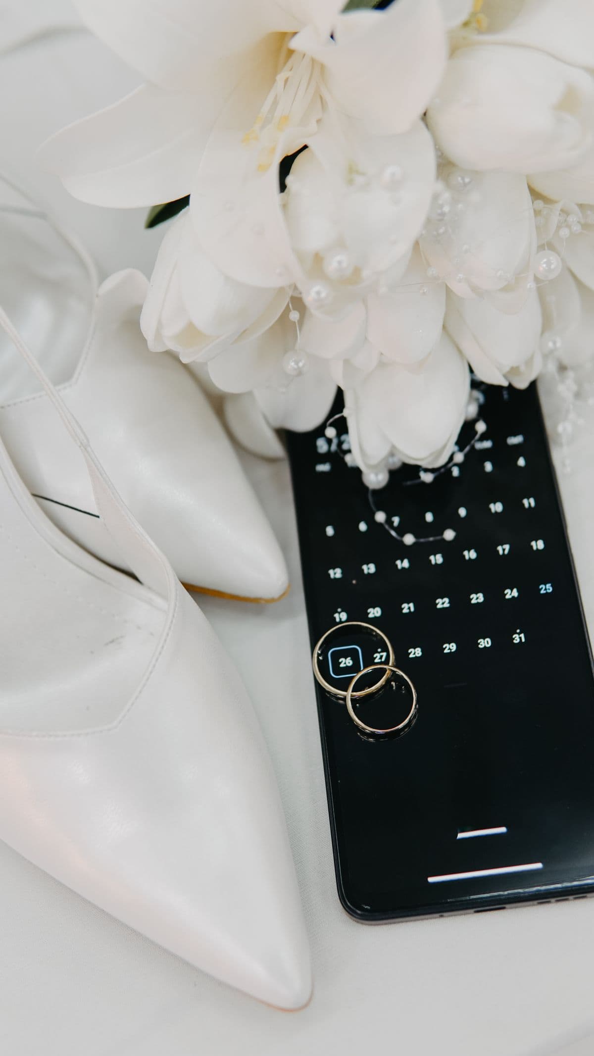 Wedding rings and smartphone with calendar app for wedding RSVP tracking and guest list planning