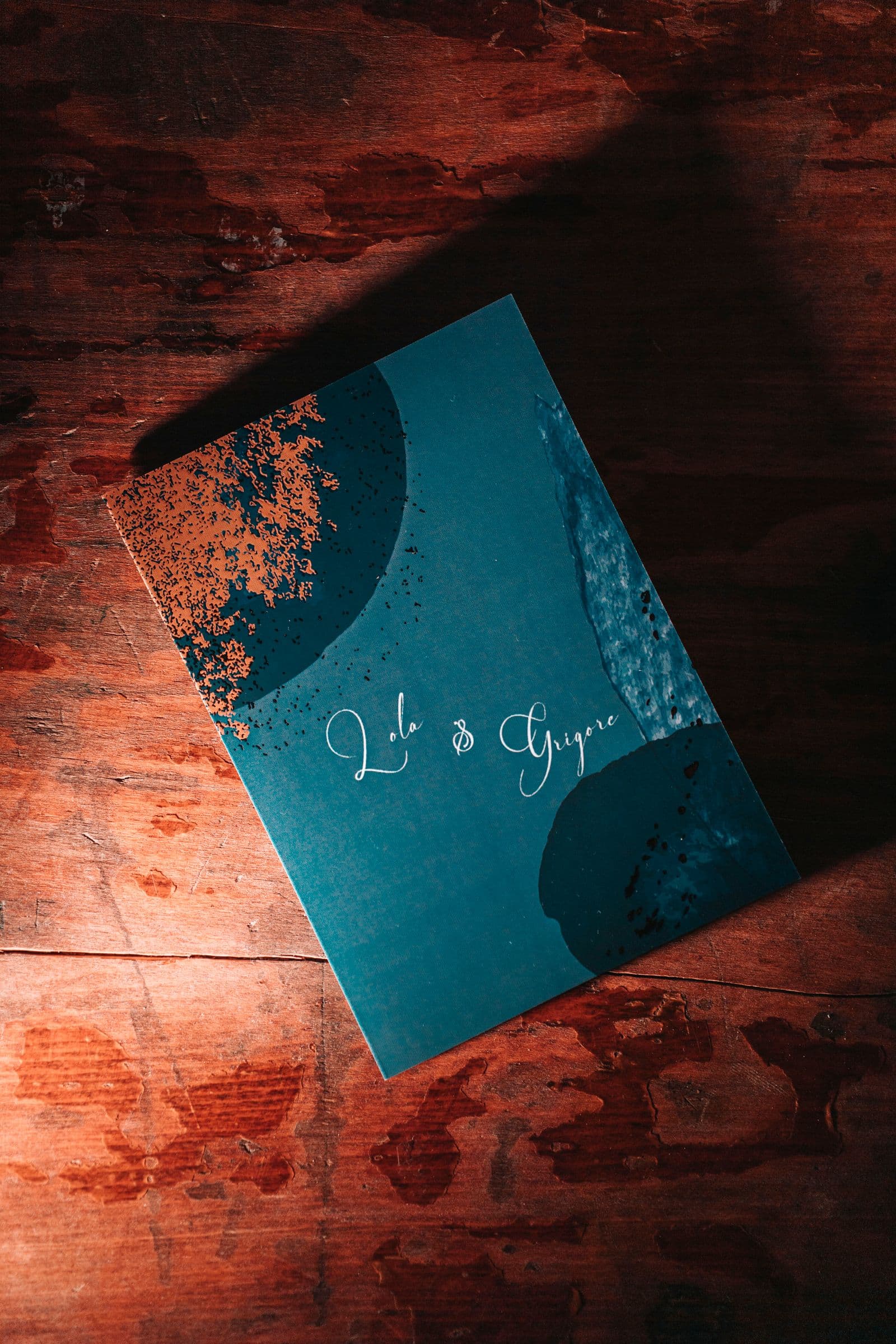 Teal wedding invitation card on a wooden desk used while drafting wedding invitation wording formal and casual lines
