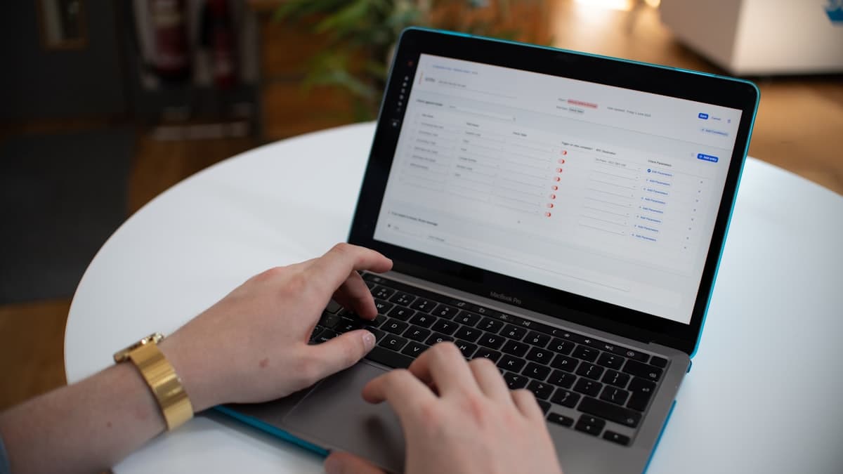 Hands typing on a laptop spreadsheet for wedding RSVP management and guest data organization