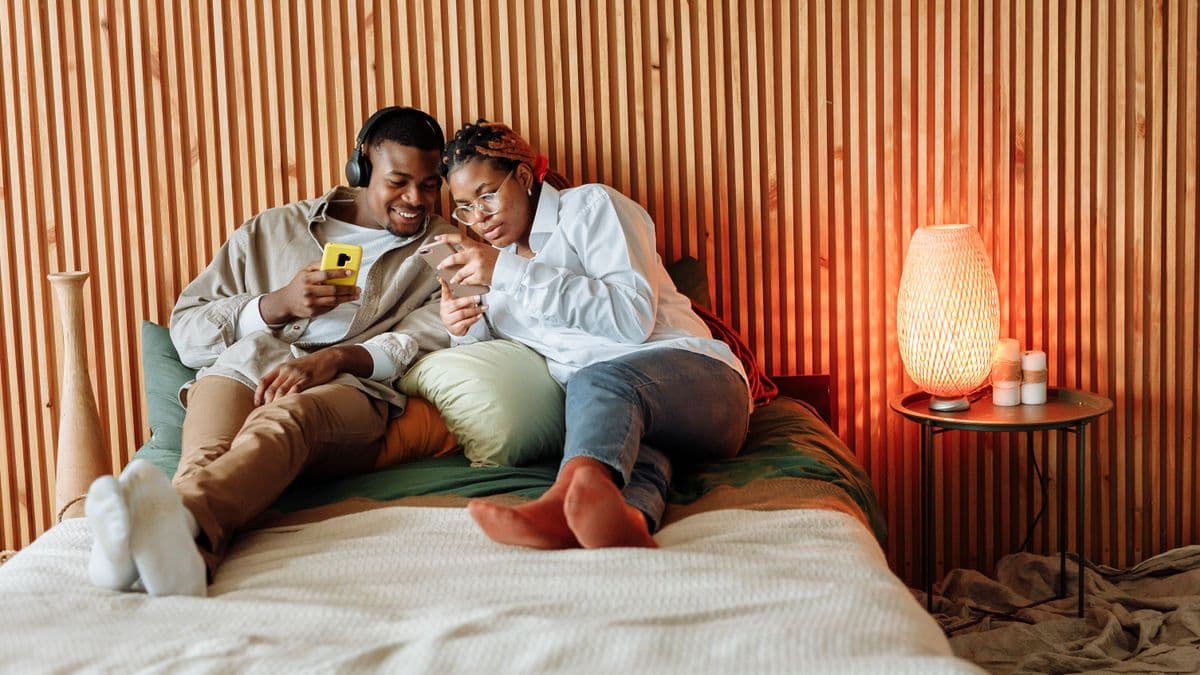 Couple comparing WithJoy and Paperless Post wedding invitation options on their phones